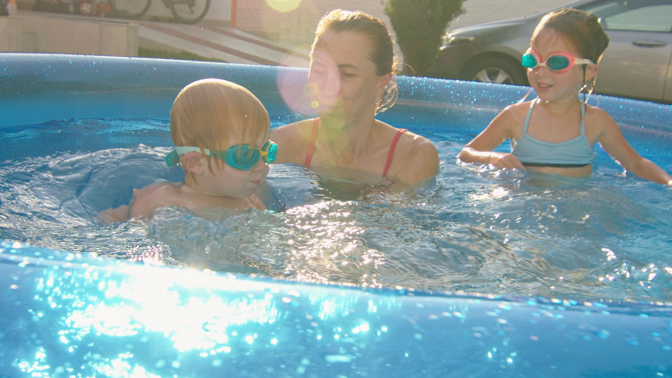 Parent and children playing in a backyard pool